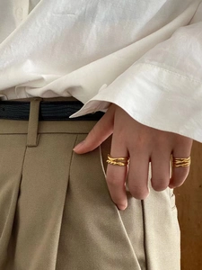 Minimalist double layer gold rings in knot and intertwined designs worn on hand