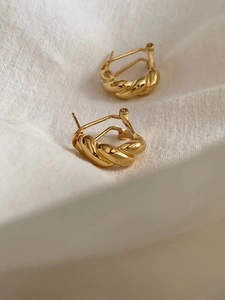 Close-up of gold twist hoop earrings with spiral texture on white fabric background