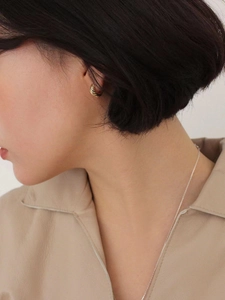Detail of twisted rope gold hoop earrings showing texture and size on a model