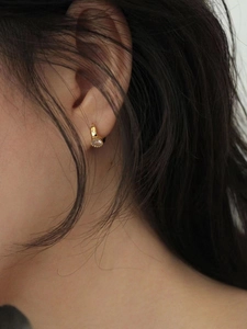 Close-up of a minimalist gold S925 silver hoop earring with a sparkling zircon stone