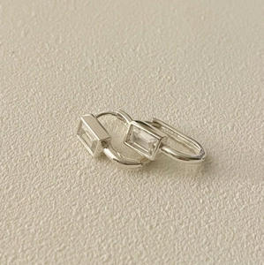 Détail de boucles d'oreilles créoles en argent serties de cristaux rectangulaires