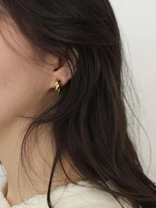 Close-up of elegant gold twisted croissant hoop earrings worn by a female model