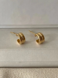 Macro detail of golden double-row C-shaped S925 sterling silver earrings on white display
