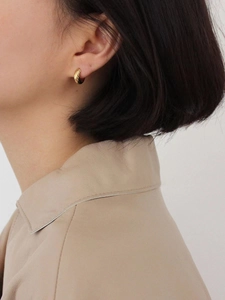 Macro shot of 925 sterling silver twisted gold hoop earrings worn on a female ear