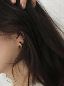 Close-up of a twisted gold hoop earring worn on a model with an elegant French style