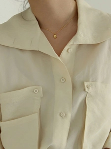 Gros plan d'un collier minimaliste en argent 925 doré avec pendentif ovale sur modèle