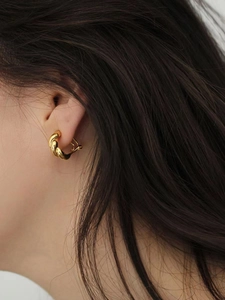 Close-up of 925 sterling silver golden twisted hoop earrings on model with dark hair