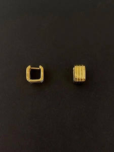 Macro shot of gold square hoop earrings with detailed vertical ribbed texture