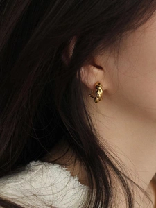 Close-up of elegant 925 sterling silver gold-plated twisted hoop earring on a model