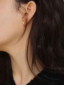 Close-up of elegant freshwater pearl earring with gold base on model ear