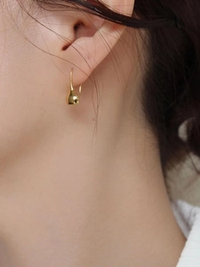 Close-up of elegant gold water drop earrings worn by a model for a modern minimalist style