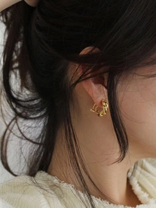 Macro shot of elegant golden twisted rope earrings worn by a model in a minimal setting