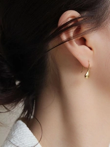 Close-up of elegant gold teardrop earrings worn by a model in a minimalist style