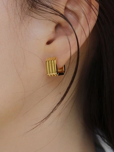 Macro shot of 925 silver square gold-plated hoop earrings with vertical ribbed texture