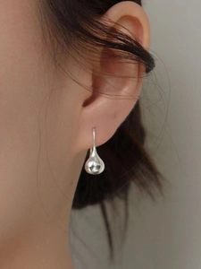 Close-up of minimalist 925 sterling silver water drop earrings worn on ear