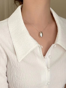 Minimalist 925 sterling silver double-sided teardrop necklace worn by model on white shirt