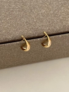 Minimalist 925 silver golden teardrop earrings with a polished mirror finish on a jewelry box