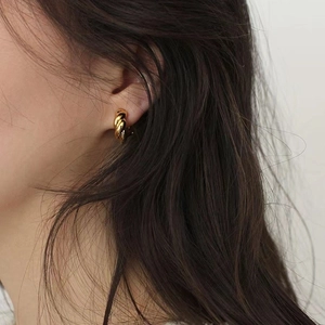 Elegant 925 sterling silver gold-plated twisted hoop earrings worn by a model