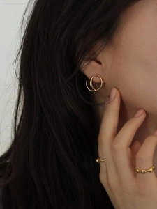 Gros plan de boucles d'oreilles créoles dorées et bagues perlées sur un mannequin