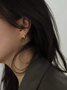 Gros plan de boucles d'oreilles doubles cercles dorées portées par un mannequin chic