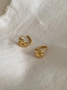 Macro shot of gold-plated S925 sterling silver hoop earrings with a twisted water drop design