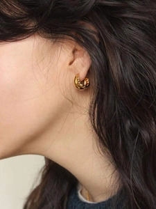 Close-up of elegant double-layered gold hoop earrings with twisted rope texture on a model