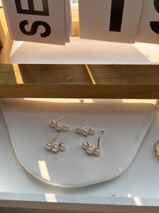 Detail of 925 sterling silver stud earrings with three white pearls in gold and silver