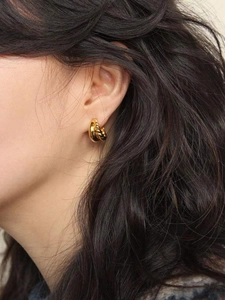 Detailed close-up of gold-plated twisted rope hoop earrings with a textured vintage finish