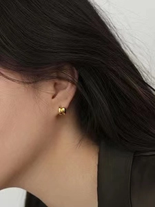Close-up of a model wearing a polished gold minimalist hoop earring for a sleek look