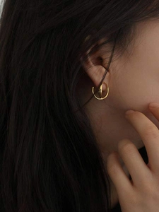 Vue macro de boucles d'oreilles créoles torsadées dorées 18K au design minimaliste