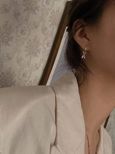 Élégantes boucles d'oreilles nœud argentées sur un mannequin dans un décor vintage