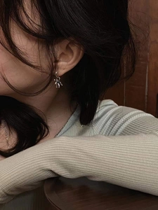 Élégantes boucles d'oreilles étoiles argentées portées par un mannequin en pull