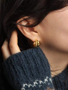 Close-up of double-layer woven gold twist earrings on model with high polish finish