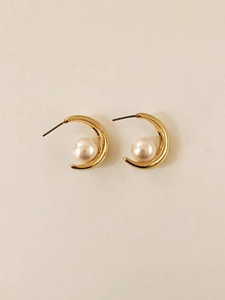 Detail of C-shaped gold-plated silver earrings with round lustrous white pearls
