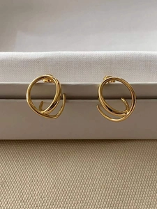 Gros plan de boucles d'oreilles dorées géométriques sur un coffret d'exposition blanc