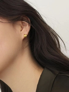 Close-up of minimalist gold heart stud earrings on model for a trendy geometric style