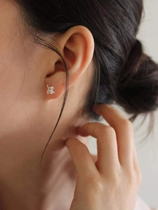 Close-up of minimalist silver balloon dog stud earrings worn by a model in soft lighting