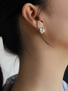 Close-up of 925 silver heart stud earrings with white pearl inlay on model ear