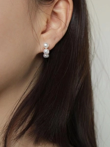 Close-up of a 925 sterling silver triple pearl stud earring on a model's ear