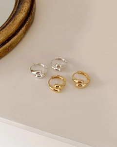 Close-up of sleek liquid lava style 925 sterling silver hoop earrings in gold and silver