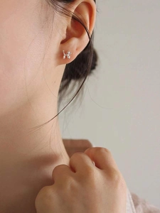 Close-up of a silver balloon dog stud earring worn on ear with polished finish