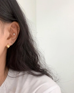 Detailed view of layered 925 silver butterfly earrings and pearl studs on model ear