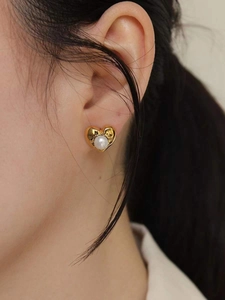Close-up of 925 silver vintage heart stud earring with a white pearl on a model's ear