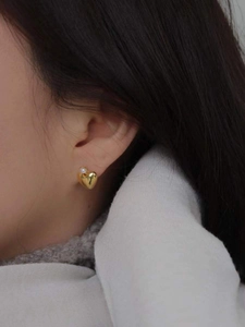 Macro detail of heart-shaped gold earring featuring a mini pearl on female model