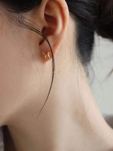 Close-up of a model wearing polished gold balloon dog stud earrings in a minimalist style