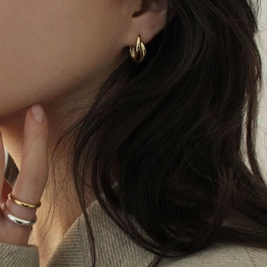 Orecchini a cerchio intrecciati in argento 925 e anelli minimalisti su modella femminile