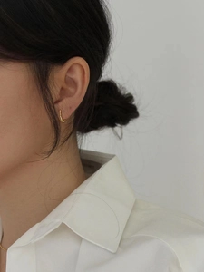 Elegant gold bow-shaped 925 silver hoop earring worn by a model in a minimalist style
