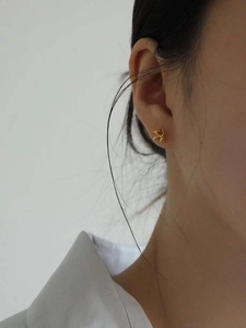 Close-up of a golden balloon dog earring worn by a model in minimalist style