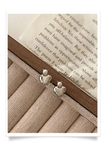 Detailed close-up of heart-shaped silver earrings with pearls on a vintage tray