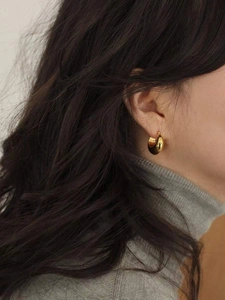 Close-up of chunky gold C-shaped hoop earrings in 925 sterling silver on model